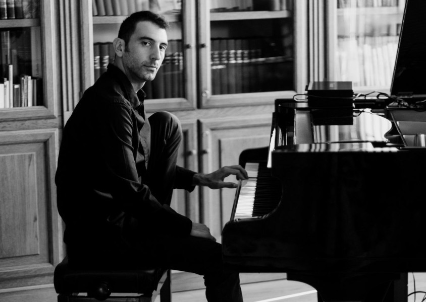 Andrea Vanzo looking at the camera while playing the piano.x