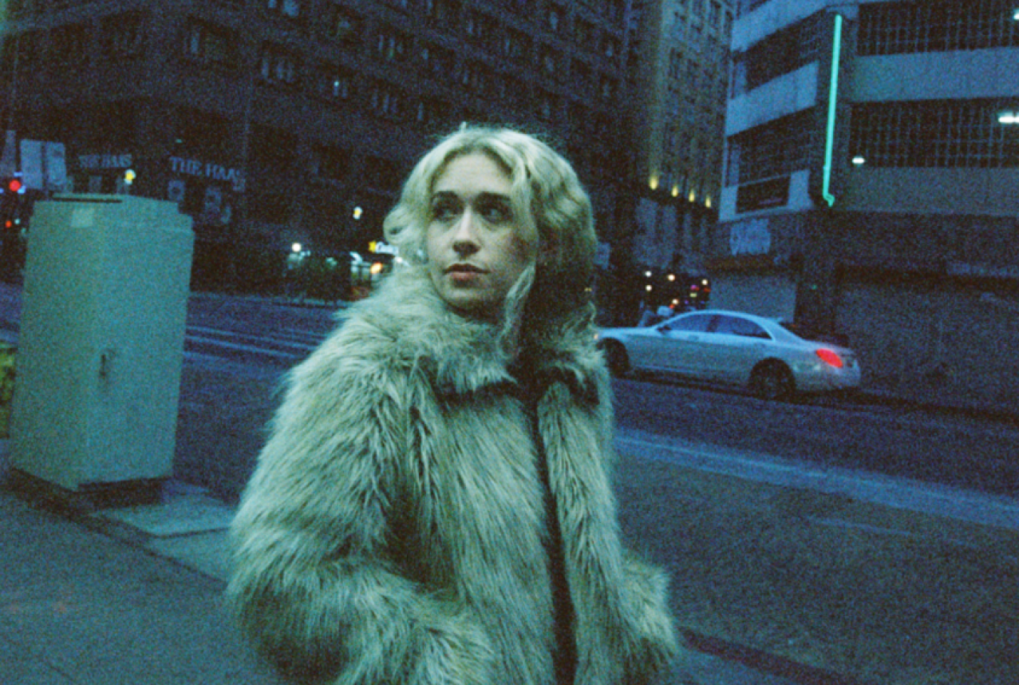 Blondshell walking in a city, looking into the distance.