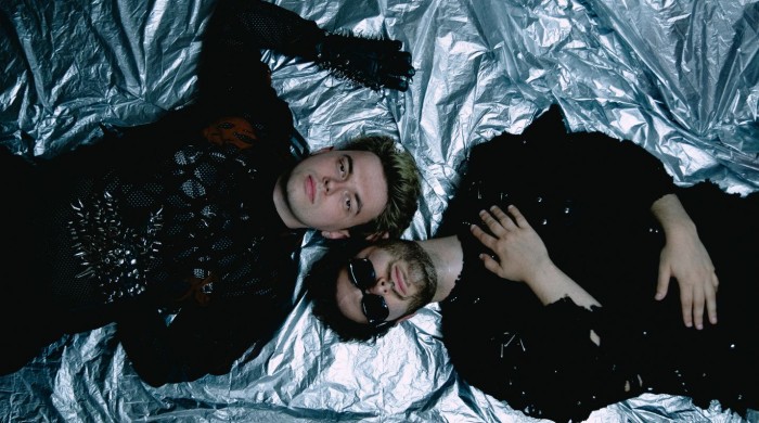 Two men dressed in black laying on a silver sheet