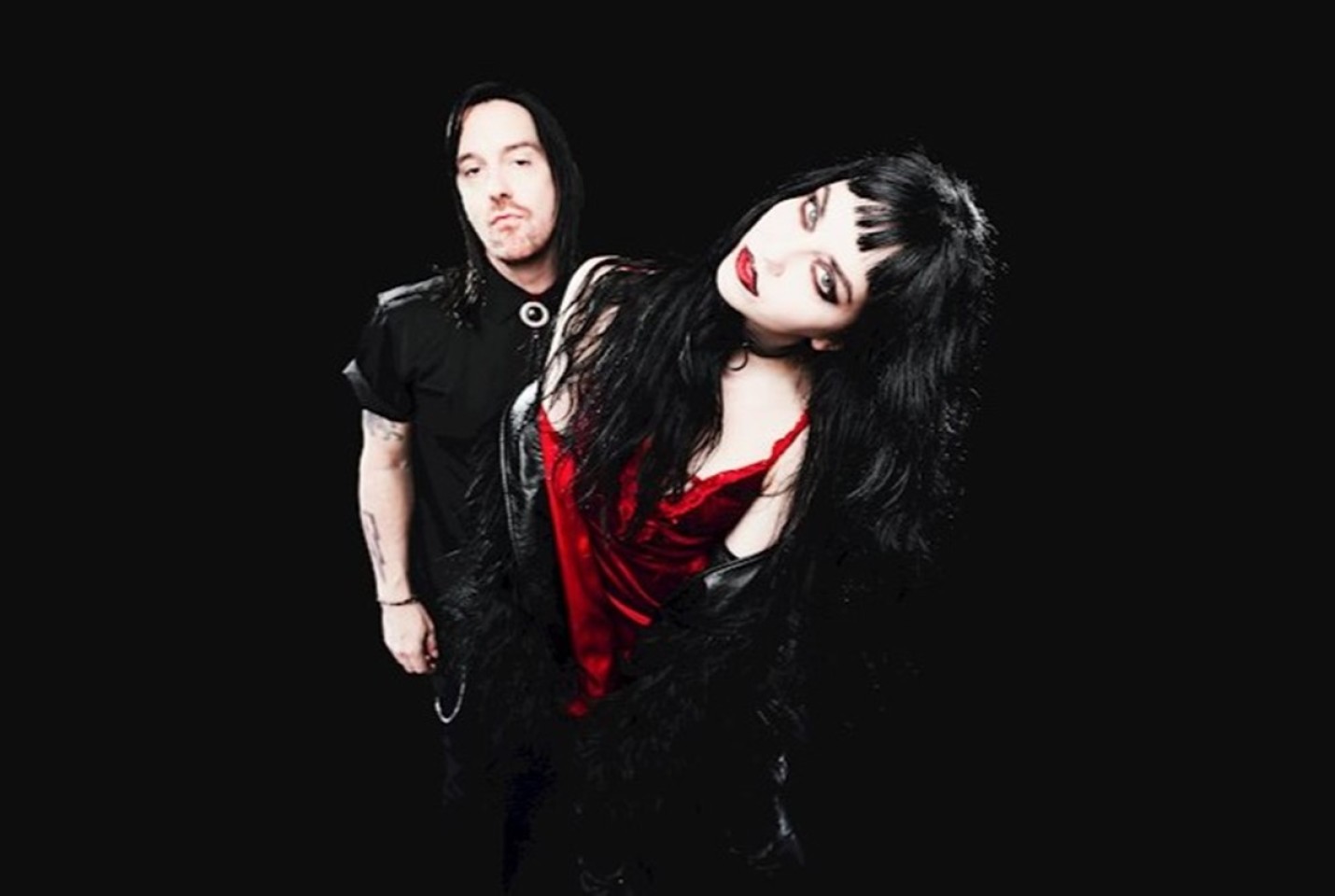 man and woman both with black hair and dark clothes with dark background