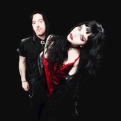 man and woman both with black hair and dark clothes with dark background