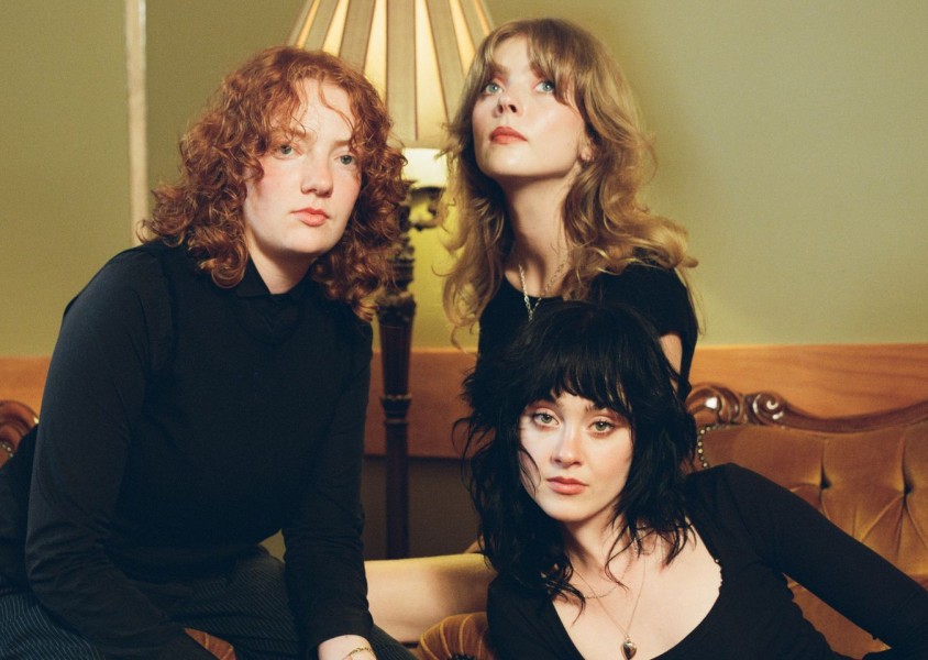 Three people sat together wearing black outfitsx