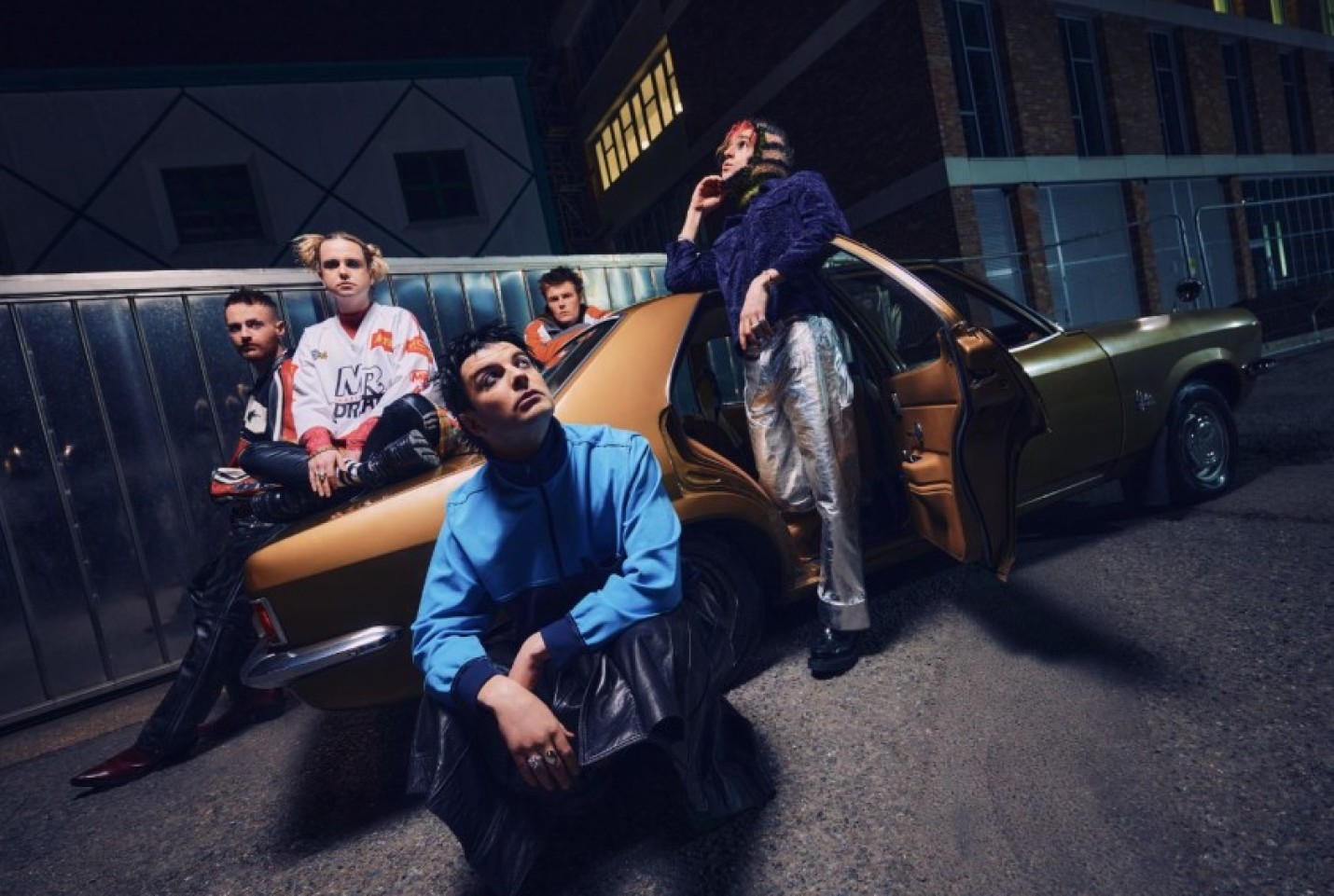 The members of Fontaines D.C., Grian Chatten, Connor Curley Conner Deegan, Carols O'Connell and Tom Coll posing in front of a car.
