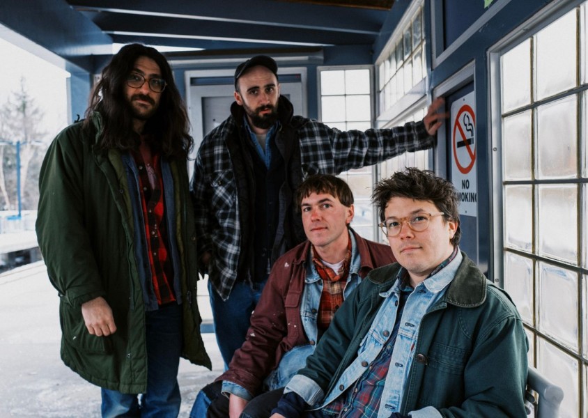 The band Friendship sat in a shelter at a train platformx