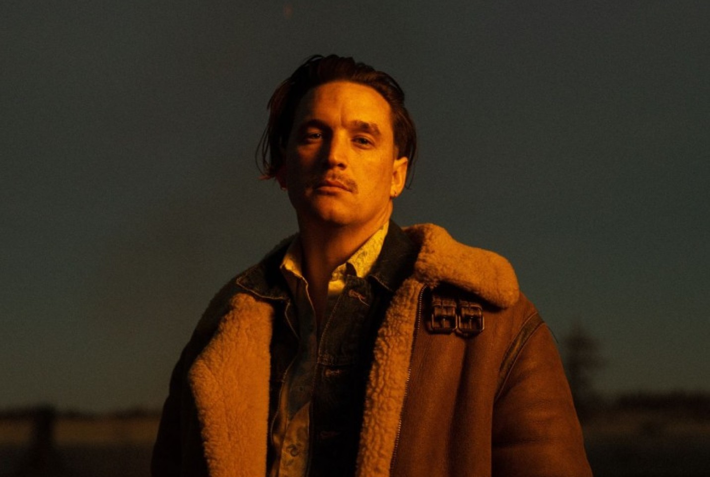Liam St. John wearing a leather coat and looking into the camera.