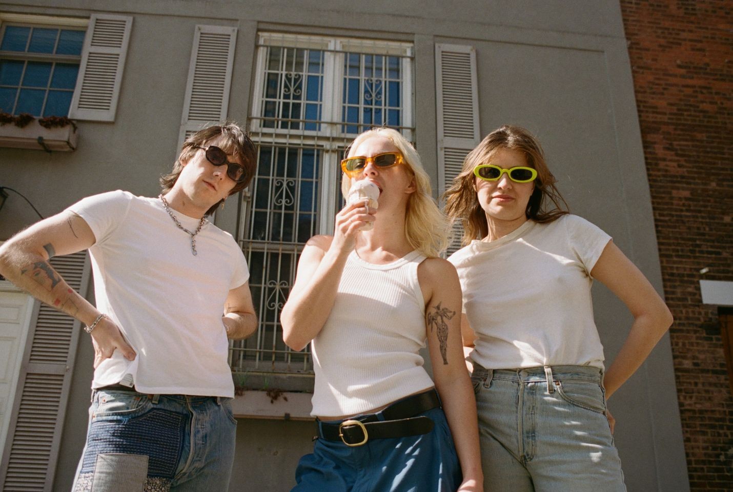 Three people in white tops, blue jeans, and sunglasses