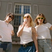 Three people in white tops, blue jeans, and sunglasses