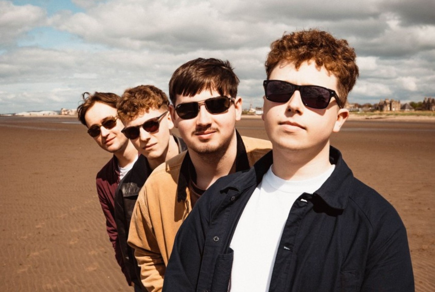 Mixed Signals members Ben Gardiner, James Armstrong, Leon Calder and Nathan Christie standing on a beach, smiling into the camera.
