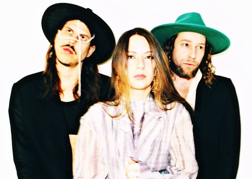 The band My Baby, with the members looking into the distance with a white backdrop behind them.x