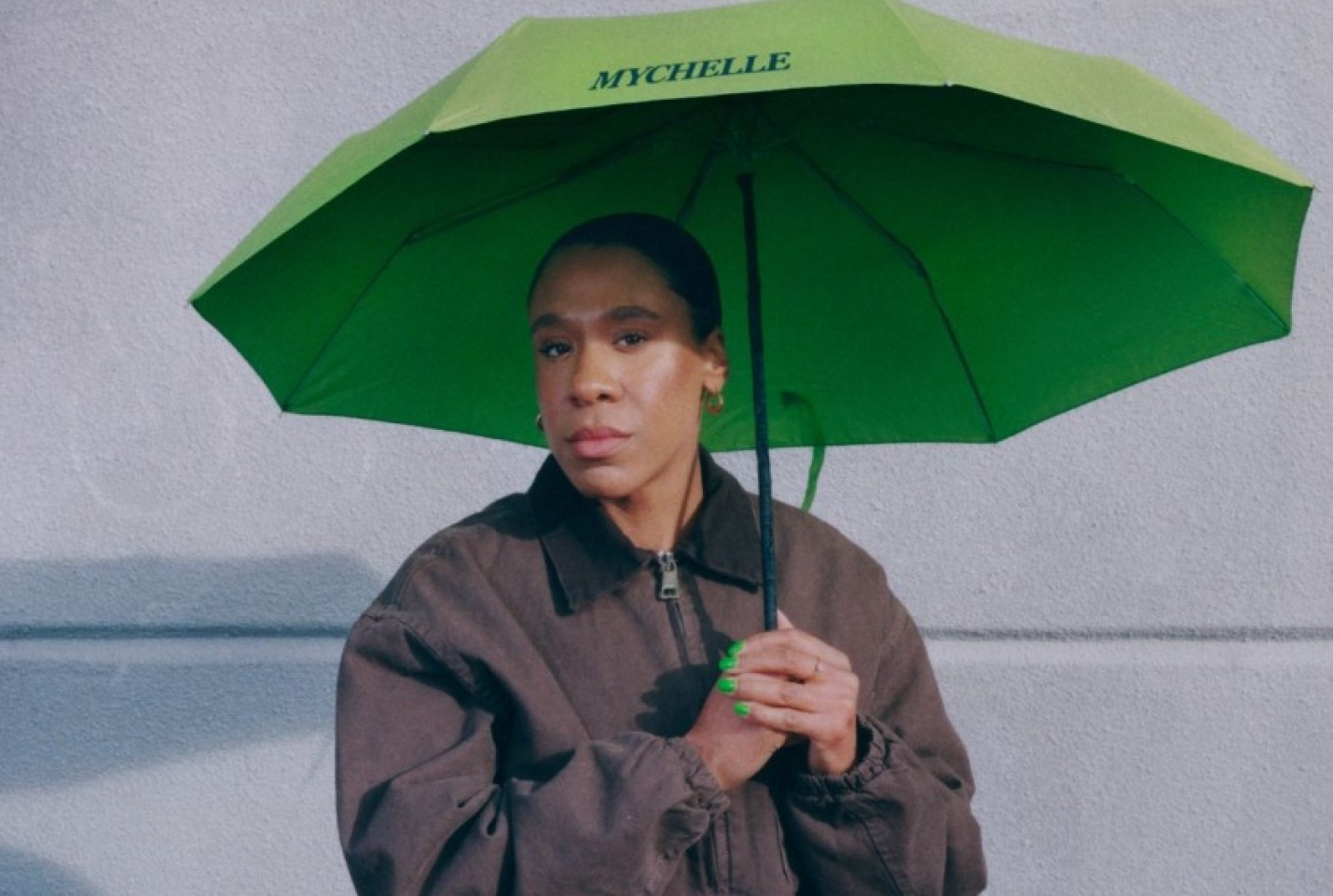 Mychelle looking into the camera while holding a Mychelle umbrella. 