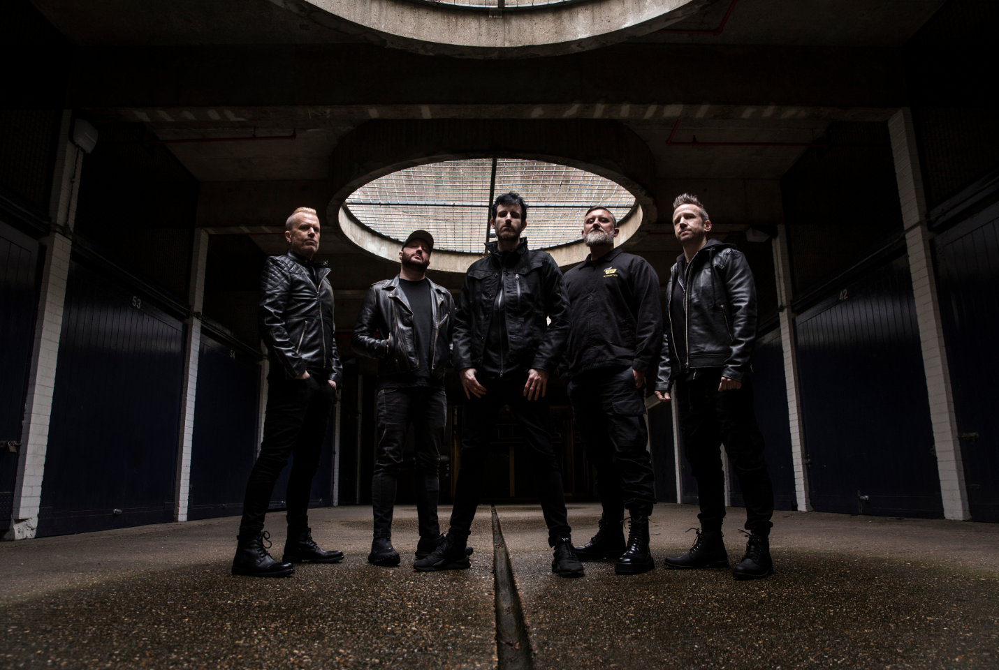 Five men standing in a dark room with dark clothing 