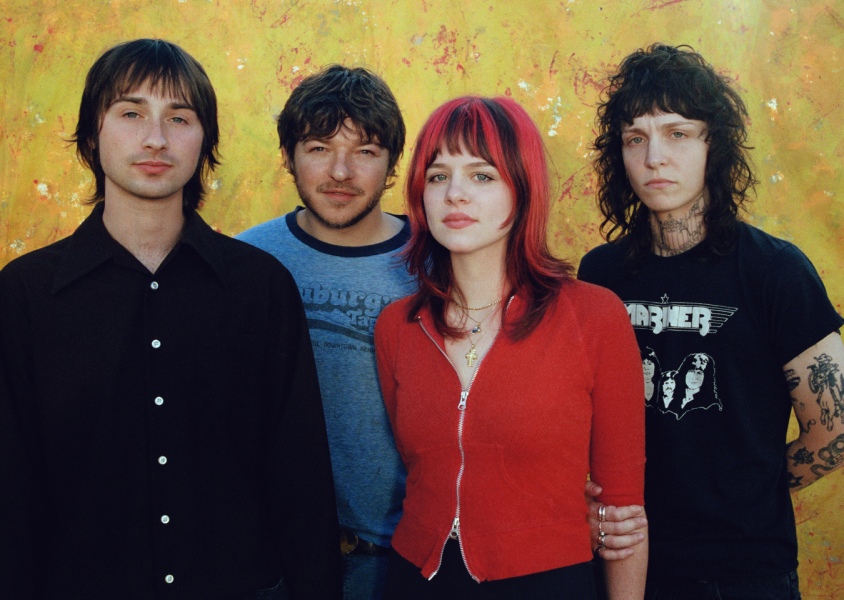 Four people stood in front of a yellow wallx