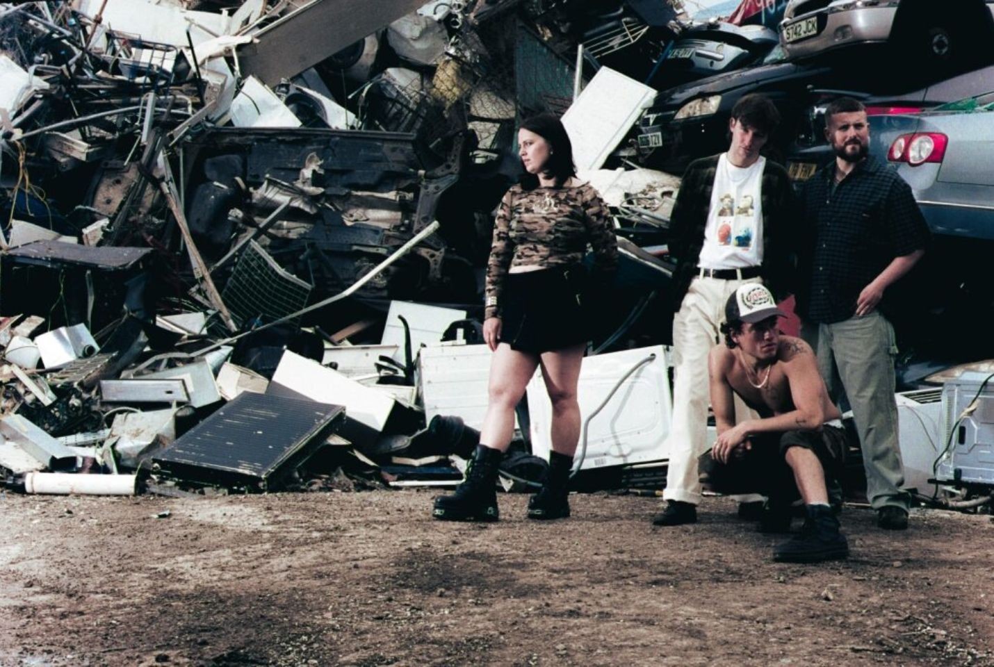 4 band members posing in a scrap metal yard