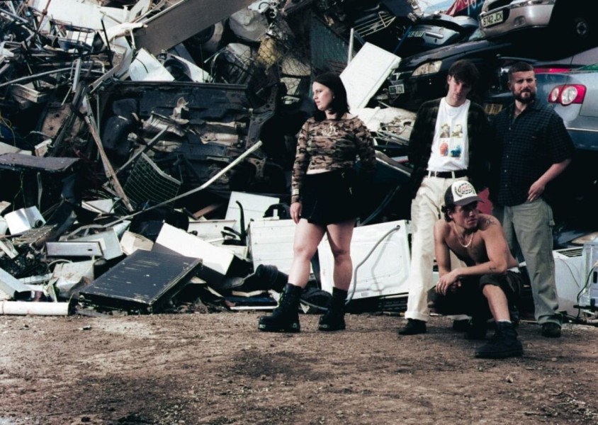 4 band members posing in a scrap metal yard x
