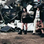 4 band members posing in a scrap metal yard