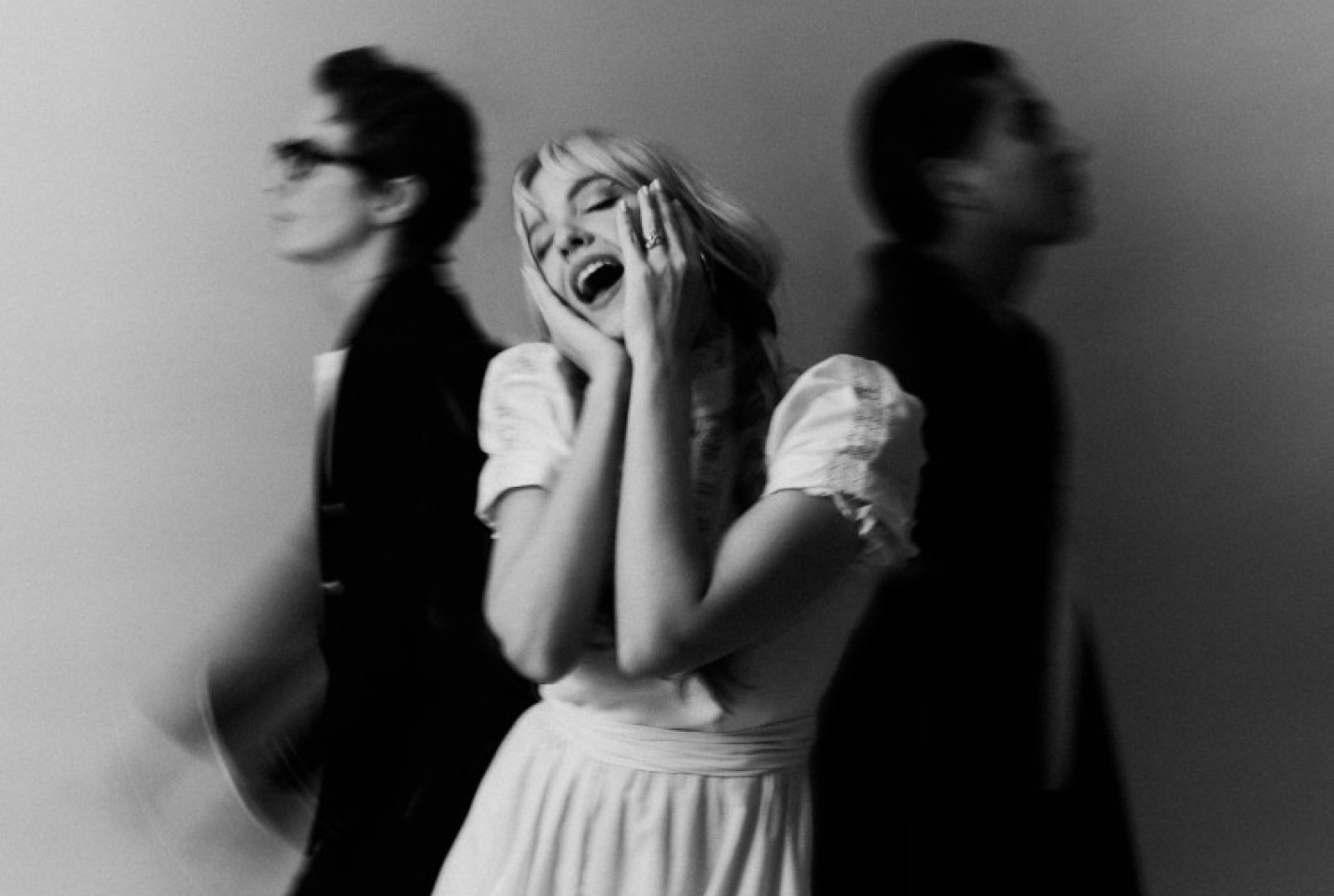 The band Sunday (1994), Paige Turner singing and Leo Newell and X walking past each other behind her .
