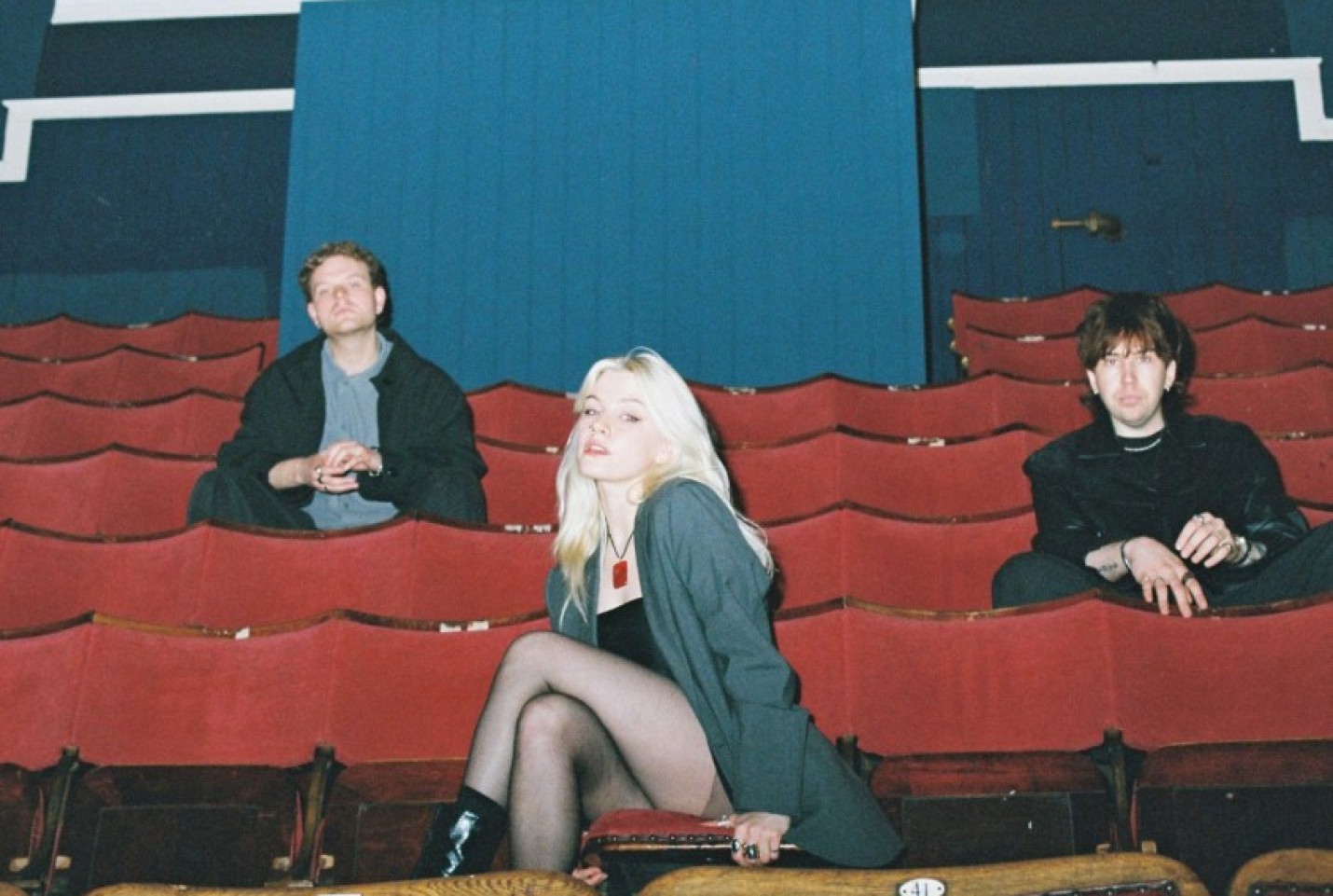 The band Swim School and the members sitting in a theatre while smiling at the camera.