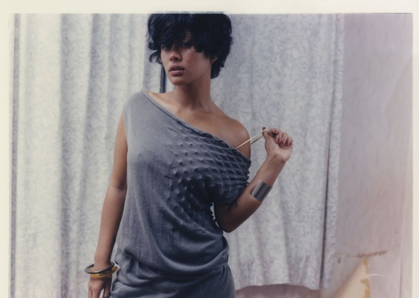 A woman with short dark hair wearing a grey knitted dressx