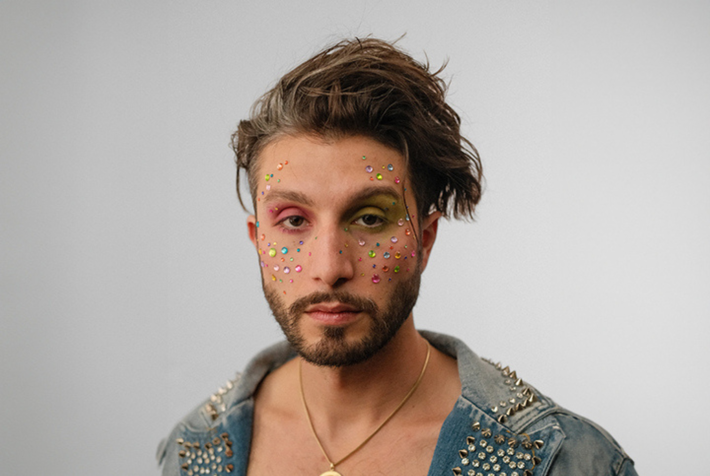 Man wearing a denim jacket with glitter on his face