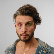 Man wearing a denim jacket with glitter on his face