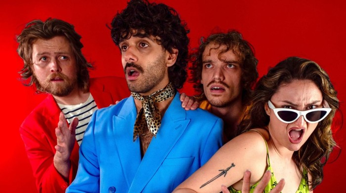 Four people stood in front of a red back drop