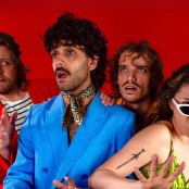 Four people stood in front of a red back drop