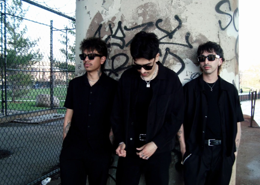 3 men posing against wall with graffiti wearing sunglassesx