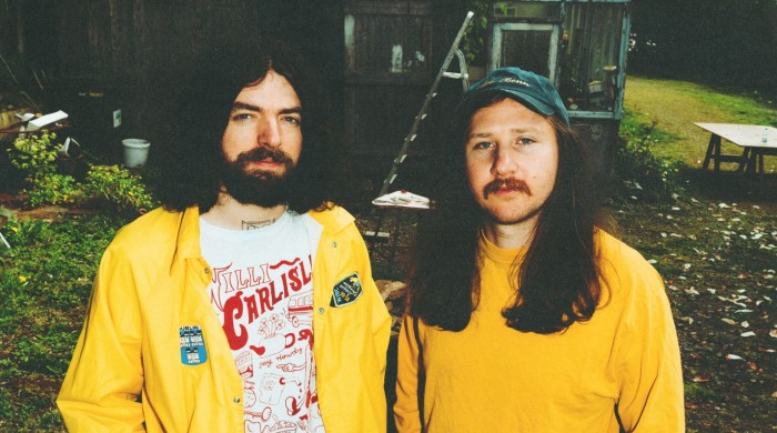Two men dressed in yellow stood in a garden