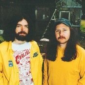 Two men dressed in yellow stood in a garden