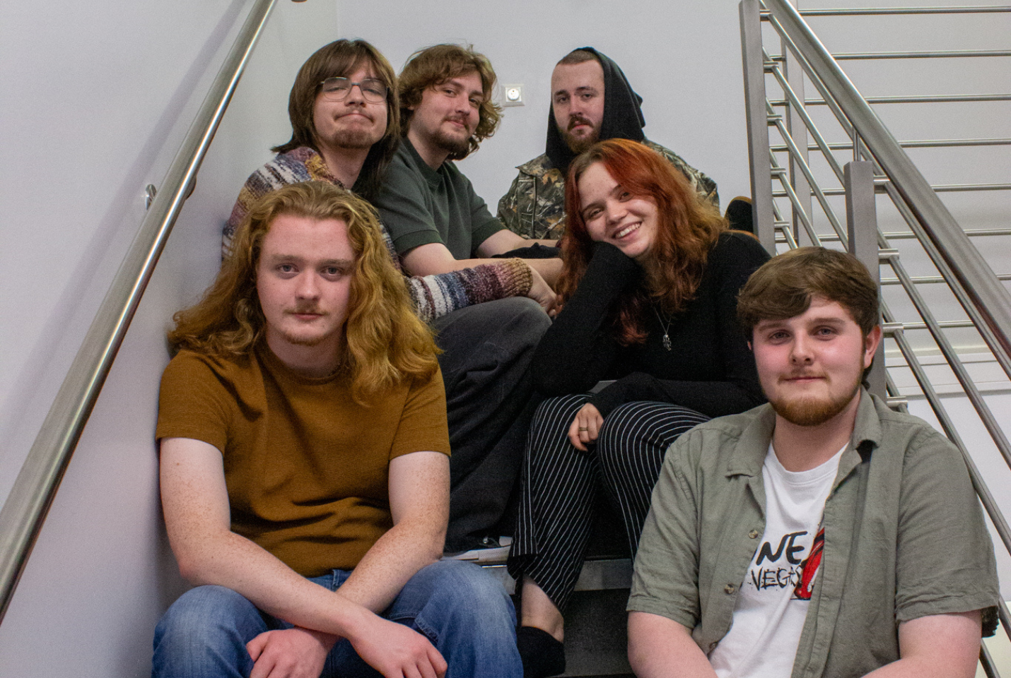 Six members of Meep looking happy sitting in a stairwell