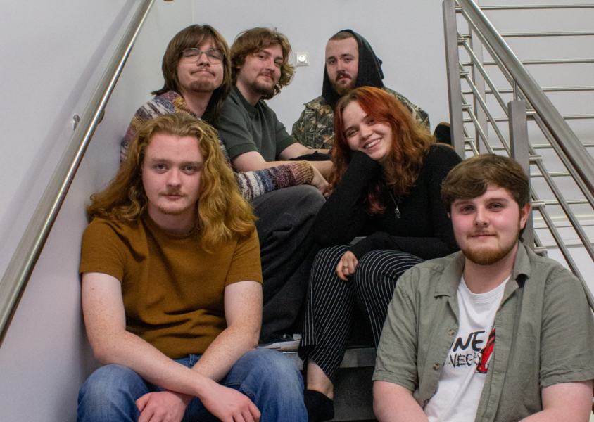 Six members of Meep looking happy sitting in a stairwellx