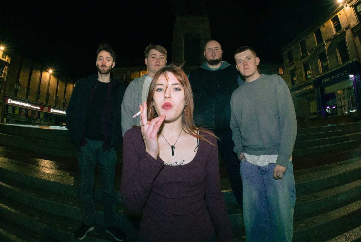 4 men standing on steps with woman smoking cigarette