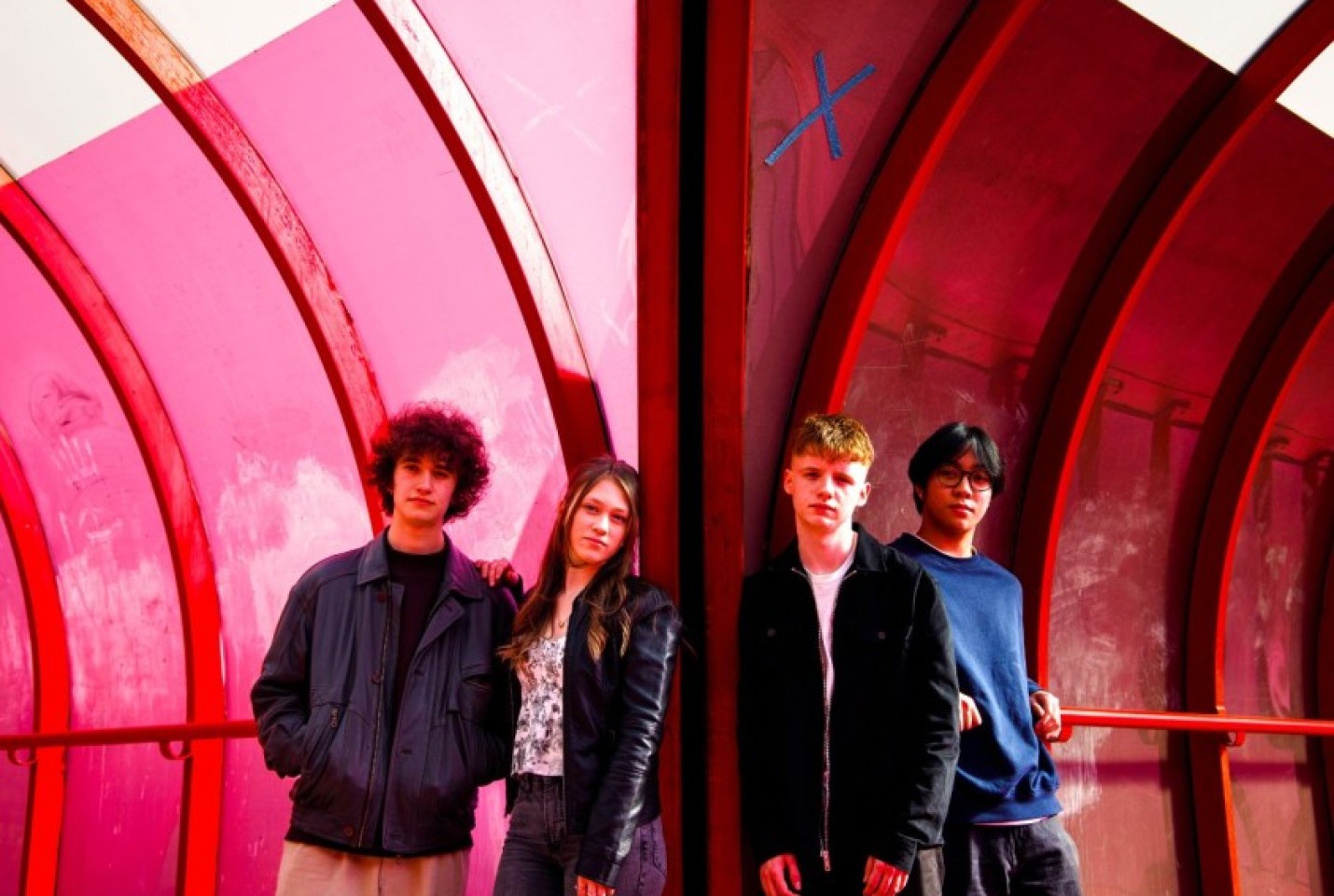 The Grapevine band, with members standing in a pink tunnel, looking at the camera with straight faces.